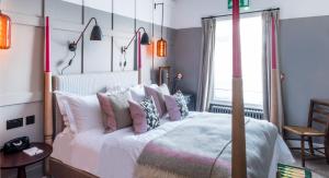 a bedroom with a bed with pink and white pillows at The Swan Hotel in Southwold