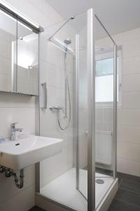 Hotel Nora في باد كروزنغن: حمام مع دش زجاجي ومغسلة