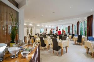 a restaurant with tables and chairs and people in the background at Hotel Nora in Bad Krozingen