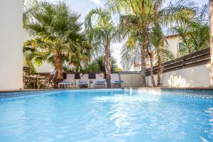 a swimming pool with palm trees and chairs at Villa Costas in Protaras