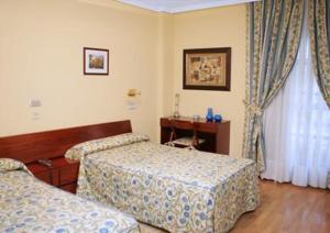 a hotel room with two beds and a desk at Hotel Isabel in Briviesca +16 photos