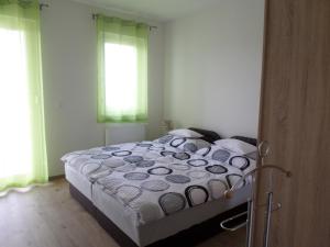 a bedroom with a bed and two windows at Lakóparki Apartman in Veszprém