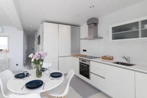 cocina blanca con mesa blanca y sillas en Apartment front line, en Moraira