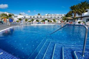 a large blue swimming pool with a hotel in the background at Relaxia Lanzaplaya in Puerto del Carmen