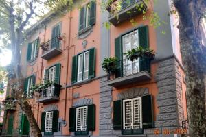 ナポリにあるVillino Chiaraの緑のシャッターと窓のあるピンクの建物