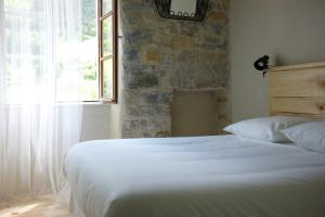 1 dormitorio con cama blanca y pared de piedra en Hôtel-Restaurant Le Parisien, en Les Vignes