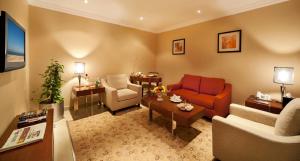 sala de estar con sofá rojo y silla en Coral Jubail Hotel, en Al Jubail