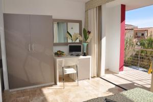 a room with a desk with a computer and a balcony at Gil's Hotel in Olbia