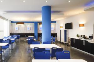 Un comedor con mesas y sillas azules. en Ibis Budget Málaga Centro, en Málaga