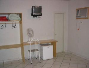 Zimmer mit einem Schreibtisch, einem TV und einem Stuhl in der Unterkunft Hotel Topazio Ltda in Umuarama