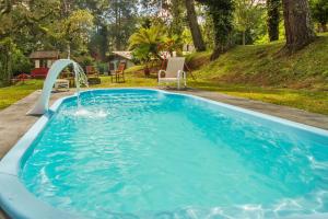 a large blue pool with a water slide at Villa Vintage Campos - Piscina e opções de suites com hidromassagem in Campos do Jordão