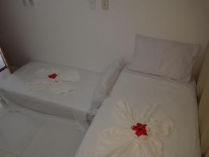 two beds with white sheets and red flowers on them at Mandakaru Residence Ap 8 in Porto De Galinhas +21 photos