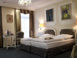 a bedroom with a large bed and a chandelier at Esplanade Spa and Golf Resort in Mariánské Lázně