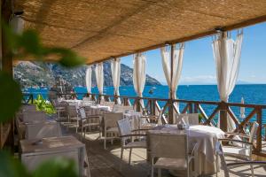 a restaurant with white tables and chairs and the ocean at Hotel Le Agavi in Positano