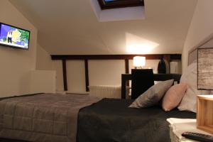 a bedroom with a bed and a tv on the wall at Résidence et Chambres d'Hôtes de La Porte d'Arras in Douai