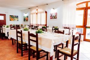 une salle à manger avec de longues tables et chaises dans l'établissement Albergo Diffuso Il Mandorlo, à Baressa