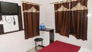 a room with a tv and a stool and curtains at Hotel Raj Palace in Ajmer