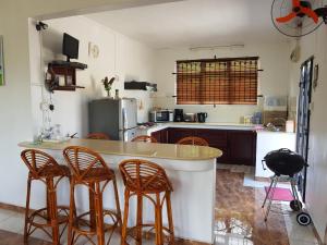 eine Küche mit einer Theke mit Stühlen drum herum in der Unterkunft Suntoo Villa Wind & Kitesurf Accommodation in La Gaulette