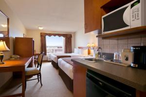 a hotel room with a bed and a kitchen with a sink at Super 8 by Wyndham Fort Nelson BC in Fort Nelson