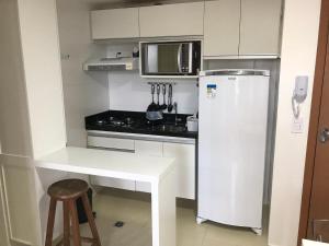 Elle comprend une petite cuisine équipée d'un réfrigérateur blanc et d'un comptoir. dans l'établissement O melhor 2 qtos da praia de Cabo Branco, à João Pessoa