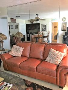 a brown leather couch in a living room with a mirror at Crescent Arms 105N in Sarasota