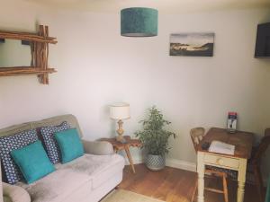 uma sala de estar com um sofá e uma mesa em The Side, Gower - Cosy, Coastal, Sea Views & Hot Tub em Horton