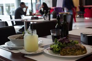 a table with a plate of food and a salad and drinks at Regency Way Montevideo Hotel in Montevideo