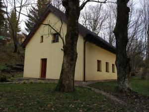a white house with two trees in front of it at Cottage Refresh in Banská Štiavnica
