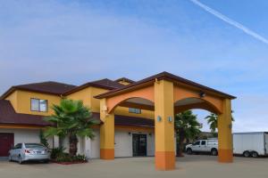 um edifício amarelo com um arco num parque de estacionamento em Scottish Inn and Suites Highway Six South em Mission Bend