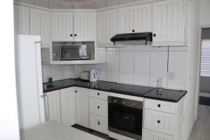 a kitchen with white cabinets and a black counter top at 41 The Bridge in St Lucia