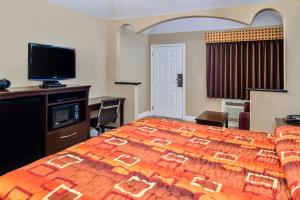 a bedroom with a large bed and a television at Scottish Inn and Suites Highway Six South in Mission Bend