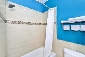 baño con bañera, aseo y paredes azules en Scottish Inn and Suites Highway Six South en Mission Bend