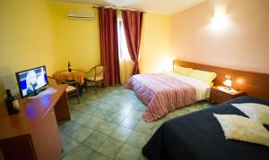 a hotel room with two beds and a desk with a television at La Lanterna in Martano