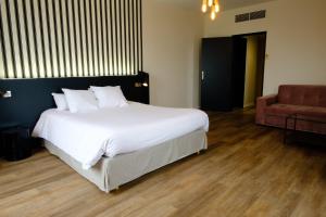 a bedroom with a large white bed and a chair at Hôtel & Spa Le Moulin de Moissac in Moissac
