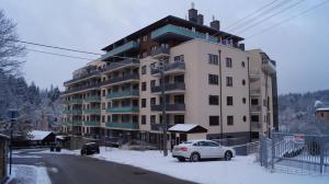 duży budynek apartamentowy z samochodem zaparkowanym na śniegu w obiekcie Ostoja Piękności w mieście Krynica Zdrój