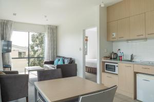 a kitchen and living room with a table and chairs at Waves in Orewa