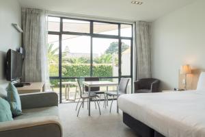 um quarto de hotel com uma cama, uma mesa e cadeiras em Waves em Orewa