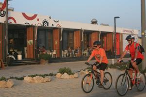 two men riding bikes in front of a building at Beach & Relax - Studio in Costa da Caparica