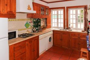 ヴィラ・ノヴァ・デ・ミルフォンテスにあるPATIO HOUSE by Nature Blissのキッチン(木製キャビネット、洗濯機、乾燥機付)