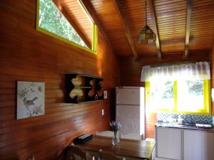 a kitchen with wooden walls and a table and a refrigerator at Chale dos Beija Flores in Gramado