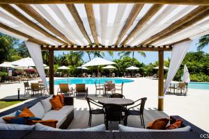 een patio met een tafel en stoelen en een zwembad bij Apartamento Terraco Buganvilias - Reserva Imbassai in Imbassai