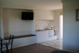 a kitchen with white cabinets and white appliances at Motel Miramar in Nambucca Heads
