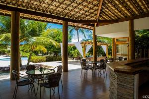 een patio met tafels en stoelen en een zwembad bij Apartamento Terraco Buganvilias - Reserva Imbassai in Imbassai