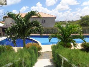 a swimming pool with palm trees in front of a house at Condomìnio Mar & Sol in Conde