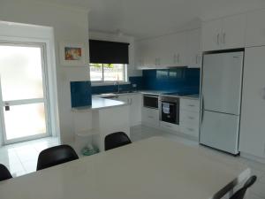 a white kitchen with a table and a refrigerator at Central Location with Fabulous Sea Views in Bridport