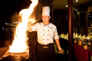 un chef parado frente a una parrilla de fuego en Halong Glory Legend Cruise, en Ha Long