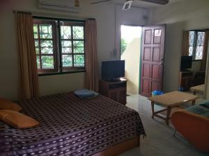 a bedroom with a bed and a tv and a door at Phuket Green Home in Karon Beach