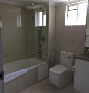 a bathroom with a toilet and a tub and a sink at Oasis Private 2 Bed Apartment in Caloundra