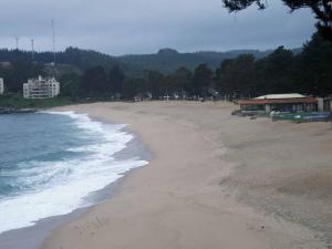 una playa de arena con edificios y el océano en Departamentos Costa Pingueral, en Tomé