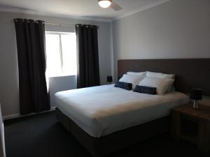 a bedroom with a large bed with a window at Oasis Private 2 Bed Apartment in Caloundra